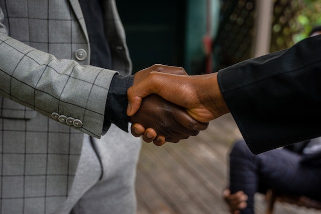 close up of two people in suits shaking hands